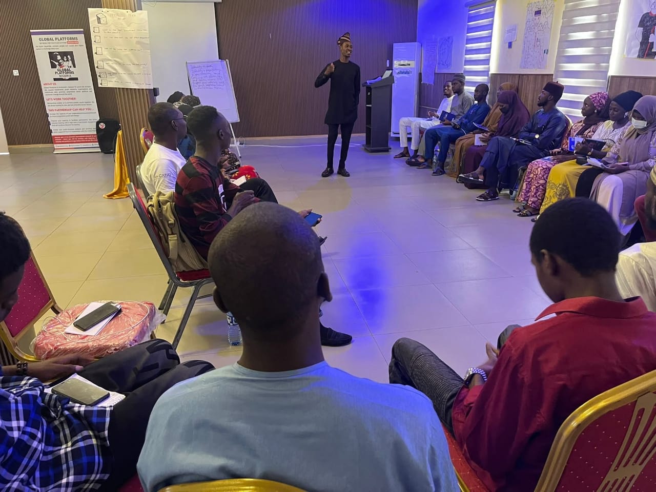 Iyasco Jeremiah facilitating a session with participants seated in a horseshoe during the Training of Trainers on youth leadership in emergencies at Rod Bola Suite, Maiduguri